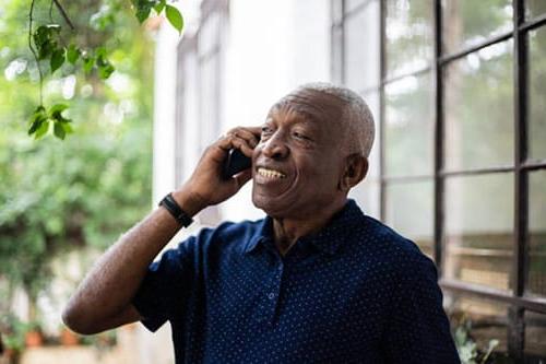 老黑人在外面微笑着讲电话